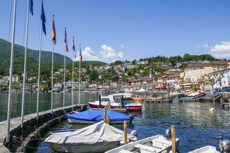 Harbor of Ascona with flags and rowing boats