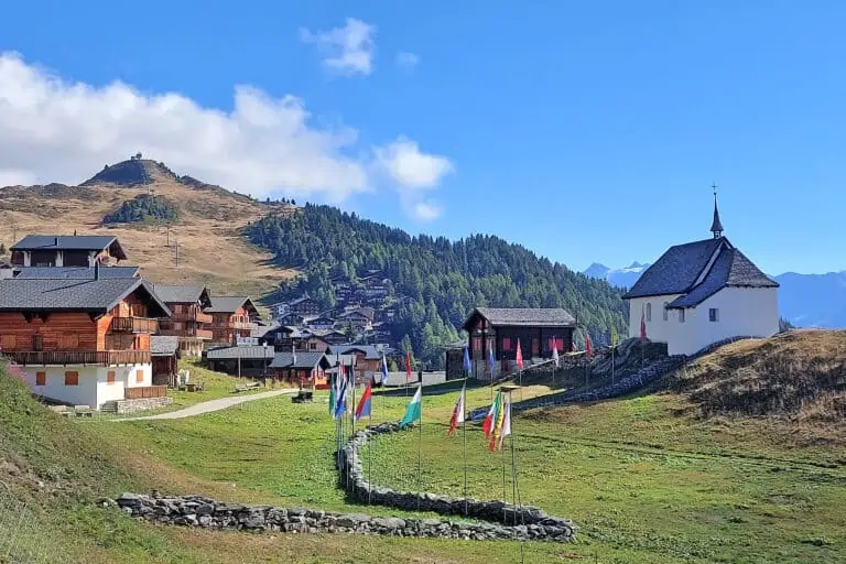 Chalets, flags and church in Bettmeralp, Upper Rhone Valley