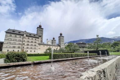 The Stockalper Palace in Brig, seen from the park with hedges and water fountains.
