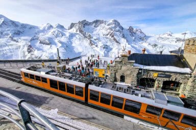 The cogwheel train station at Gornergrat, with skiers and the Dufourspitze in the background.