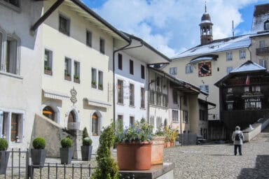 Old town square, white facade and spring flowers in the old village center of Gruyères.