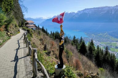 Path between Harder Kulm funicular and restaurant, with Lake Brienz and wood sculpture of a flag waver.