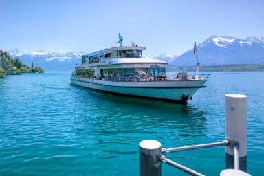 A boat on Lake Thun and the Bernese Alps seen from Hilterfingen.