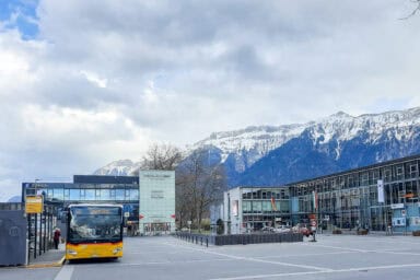The Interlaken Ost station square with bus, fountain, and Coop supermarket.