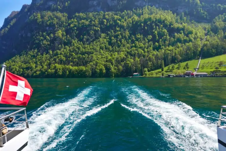 Boat trail and Swiss flag from catamaran boat near Kehrsiten-Bürgenstock