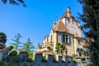 The castle of Oberhofen, surrounded by a wall and pine trees.