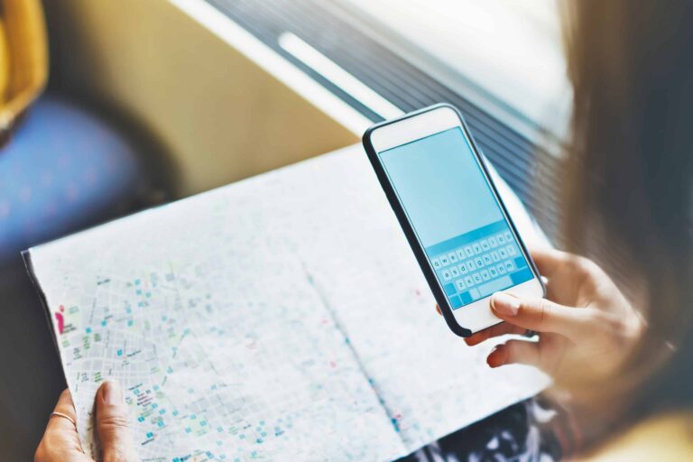 Frau mit Karte und Mobiltelefon im Zug